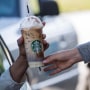 A barista passes a drink order to a customer at a Starbucks drive-thru in Rodeo, Calif.,